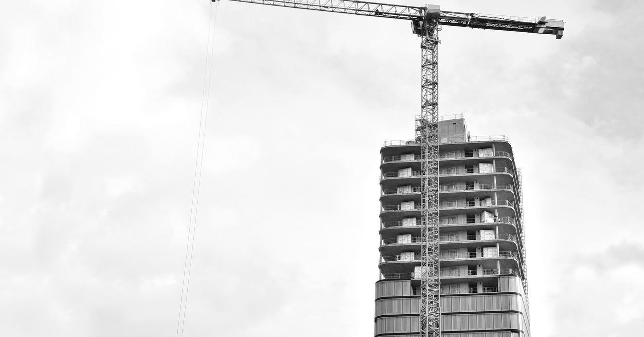 A building under construction with a tower crane above the frame