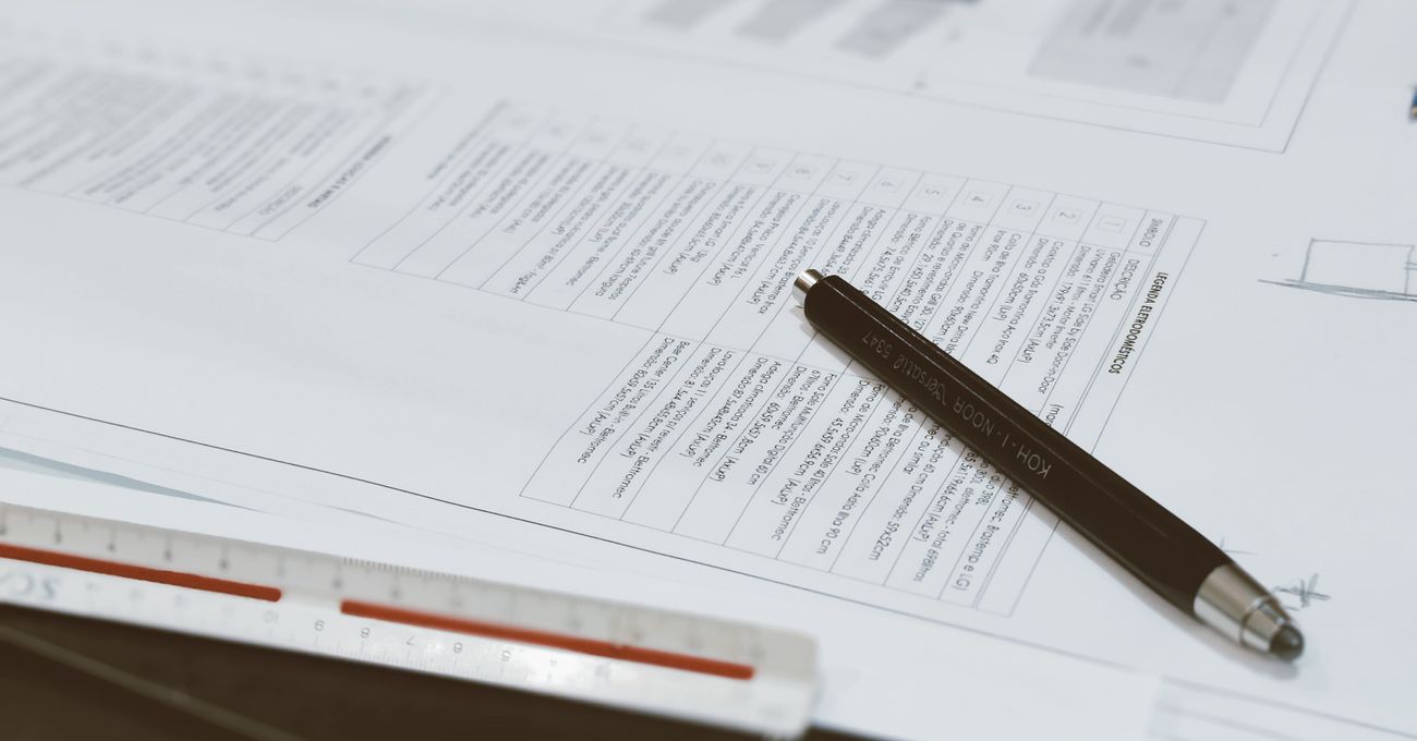 Architectural drawings on a desk with a scale ruler and pen
